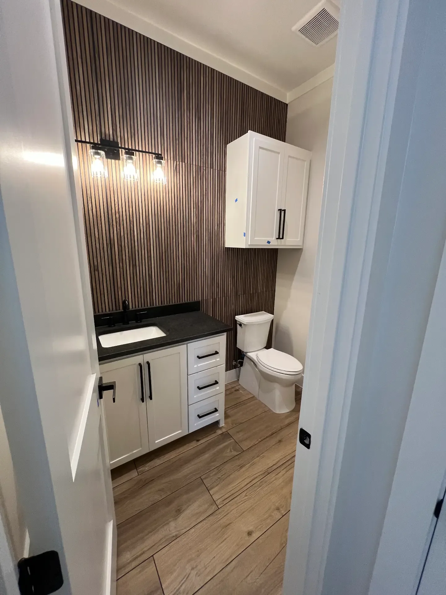 Secondary bathroom with a wood-slat accent wall in a Venado Construction new home build
